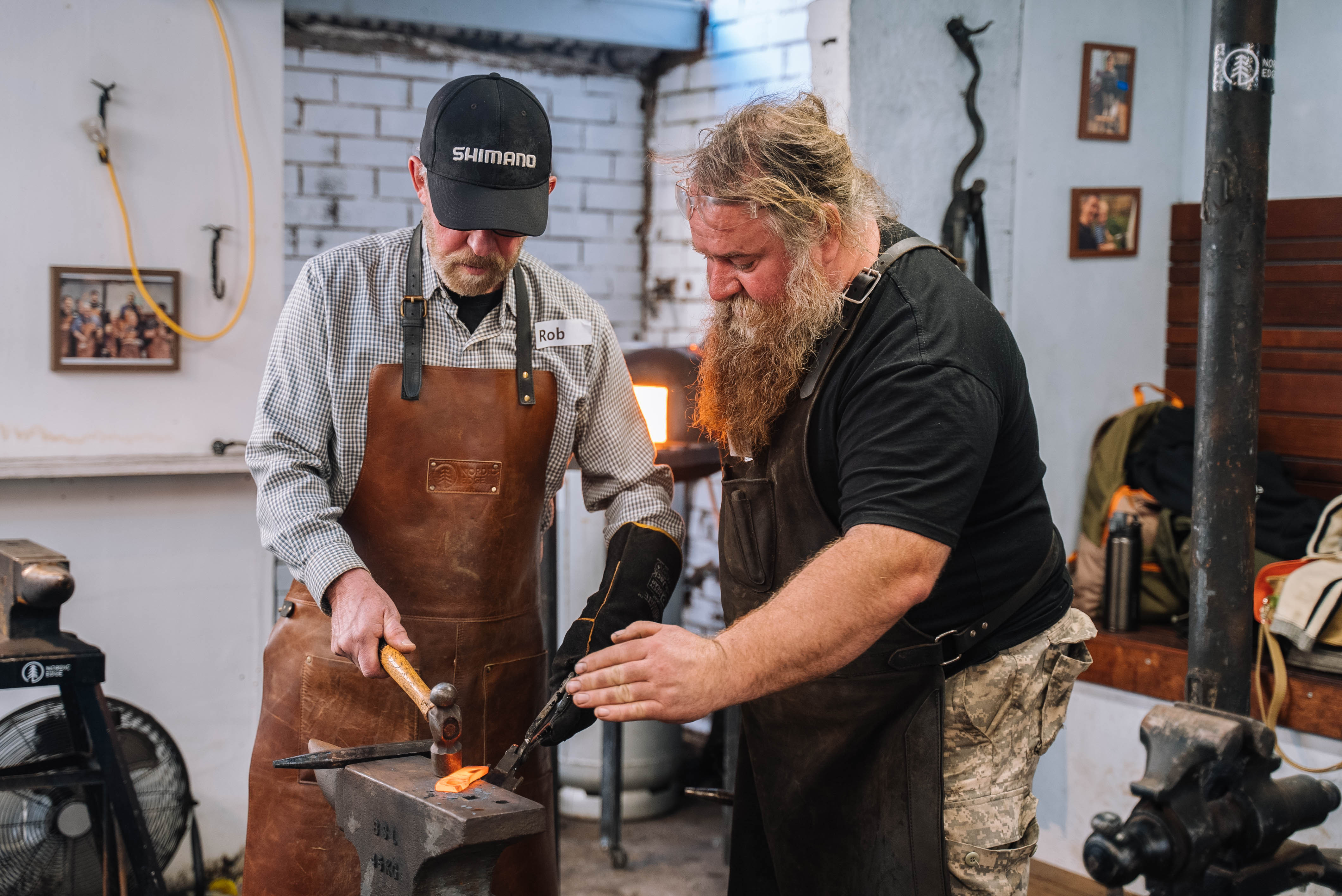 Teacher helping a man in a blacksmithing workshop